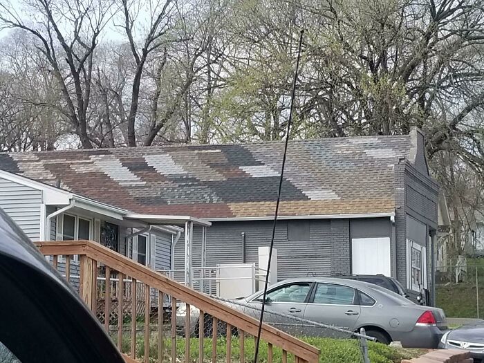 A hilariously bad DIY example of a house with a mismatched, patchwork roof, showcasing a poor attempt to fix it.
