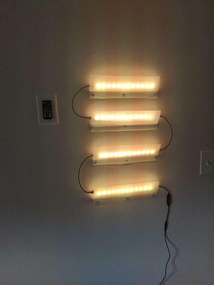 A hilariously bad example of DIY: four strips of LED lights haphazardly wired together and mounted on a wall, showcasing a DIY lighting project.