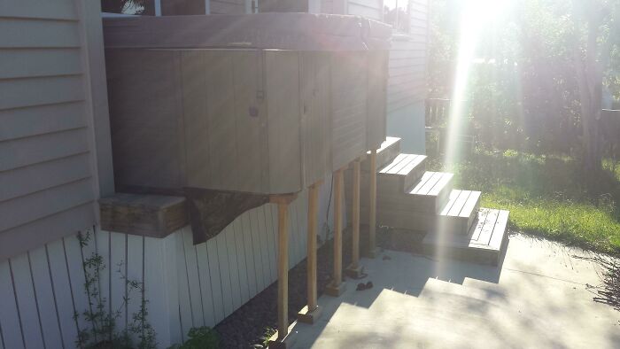A hilariously bad example of DIY: a hot tub precariously propped up on wooden stilts next to a house, illustrating DIY fails.