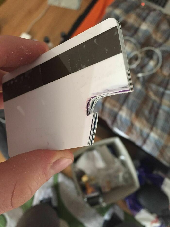 Hilariously bad DIY: A close-up of a stack of plastic cards, poorly cut and damaged, held by fingers.