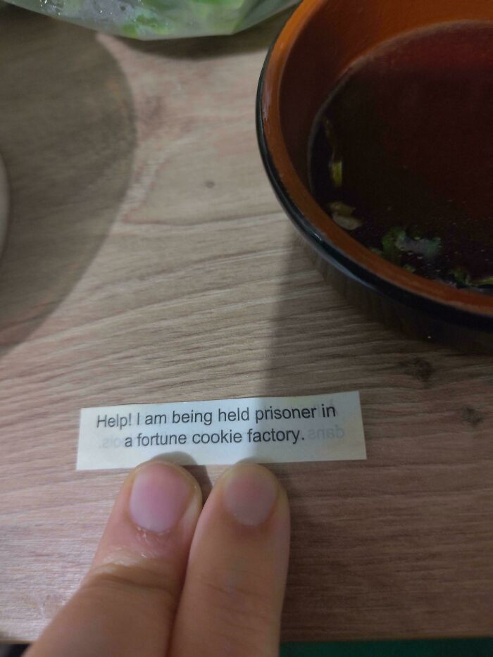 A fortune cookie message saying Help! I am being held prisoner in a fortune cookie factory, a weird and unexpected moment.
