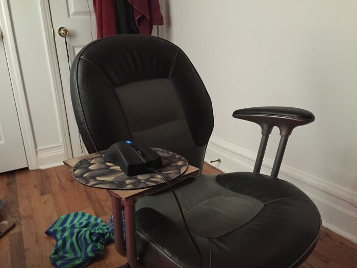 A hilariously bad DIY computer chair with a cardboard mouse pad attached to an armrest.