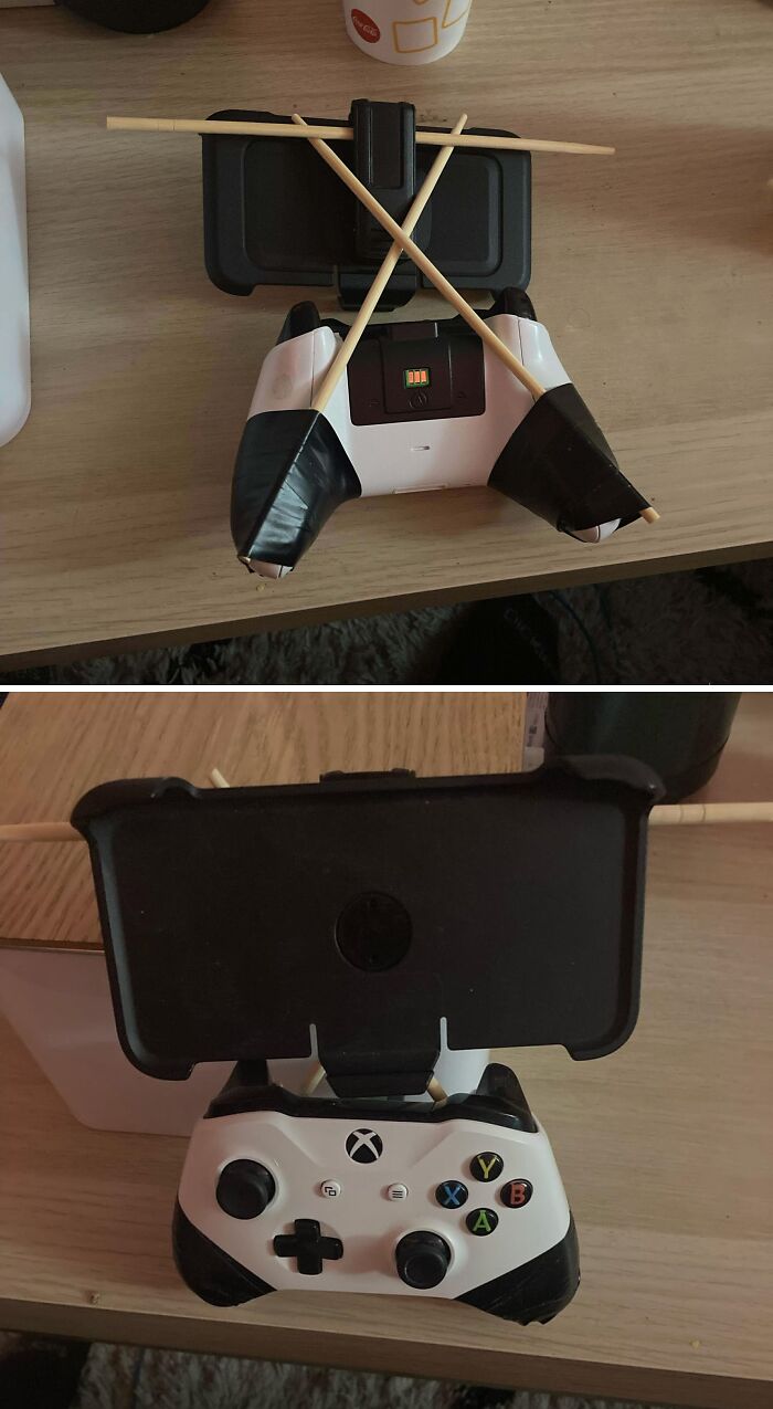 A hilariously bad DIY setup: chopsticks taped to an Xbox controller holding a phone, demonstrating a poor fix.