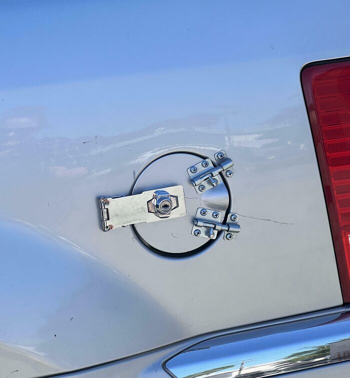 A car's fuel cap secured with multiple latches and a padlock, an inventive clever solution.
