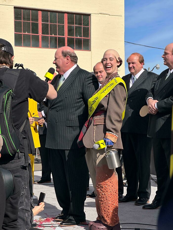 A woman in a costume laughing at an outdoor event, a weird and unexpected moment.