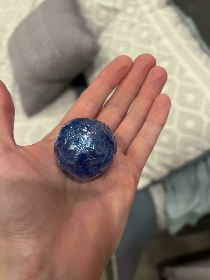 Hand holding a small, shiny blue ball, an unexpected moment that made the day interesting.
