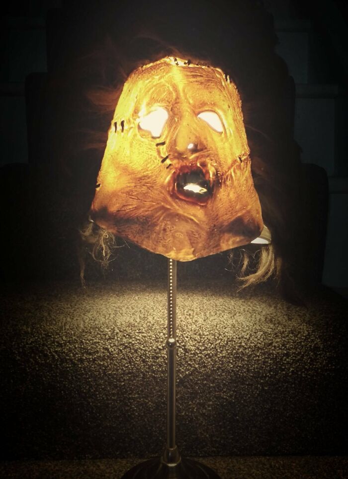 A DIY horror-themed lamp with a distorted, stitched face for the lampshade, emitting eerie light.