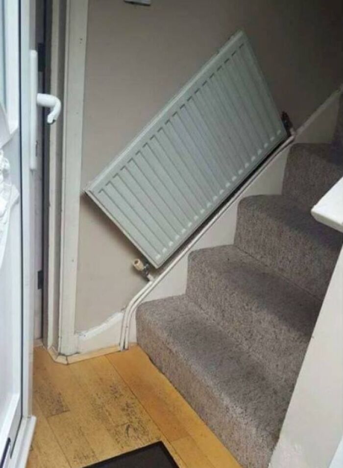 A radiator installed diagonally on a wall above a staircase, a bad example of DIY.