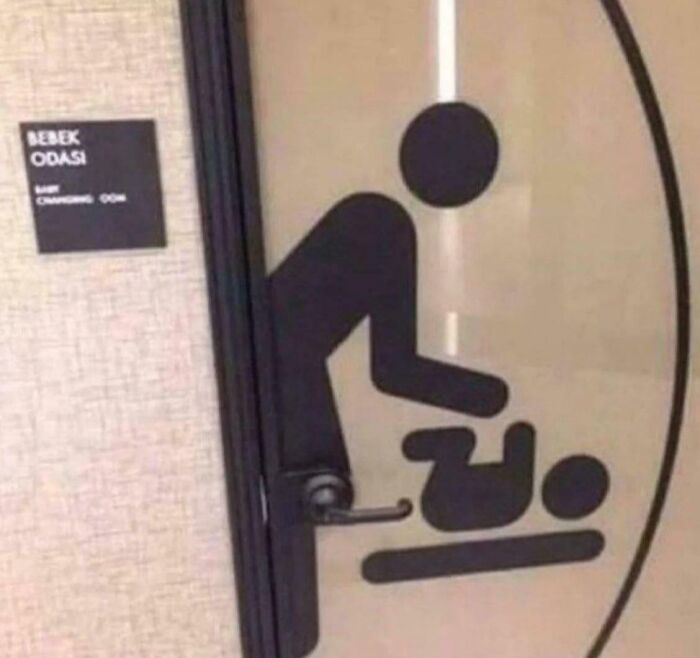A changing room sign depicting an adult changing a baby, but the door handle is awkwardly placed on the baby's head, a funny fail.