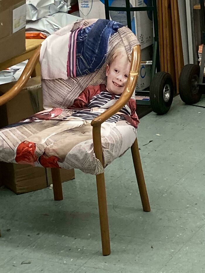 A young child with a wide smile sits in a patterned armchair, a delightful and interesting moment.