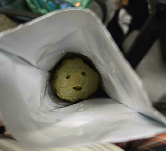 A pickle with an unexpected face inside a bag, making the day more interesting with its weird expression.