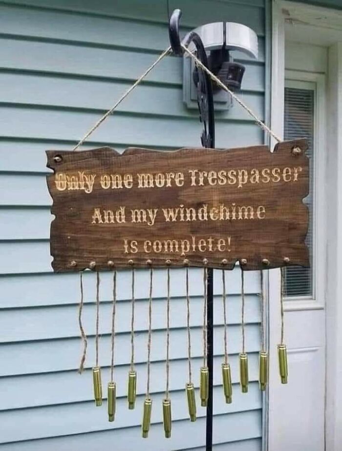 A wooden sign with a mildly infuriating obstacle message for trespassers, humorously threatening to make them part of a wind chime.