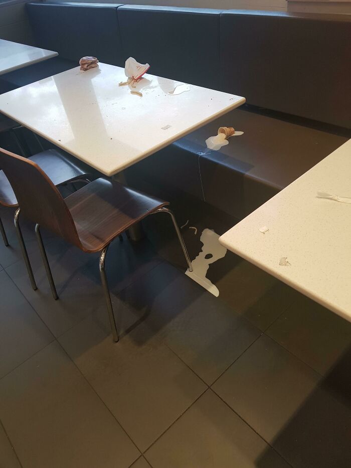 A restaurant table with spilled food and drink on the floor, an infuriating obstacle.