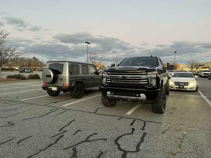 A large truck and an SUV parked over multiple spaces, a mildly infuriating parking obstacle.