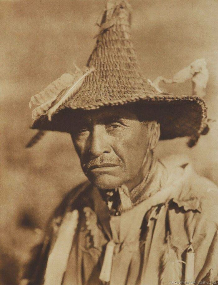 A close-up of a man in a feathered straw hat, a rare American history photo.