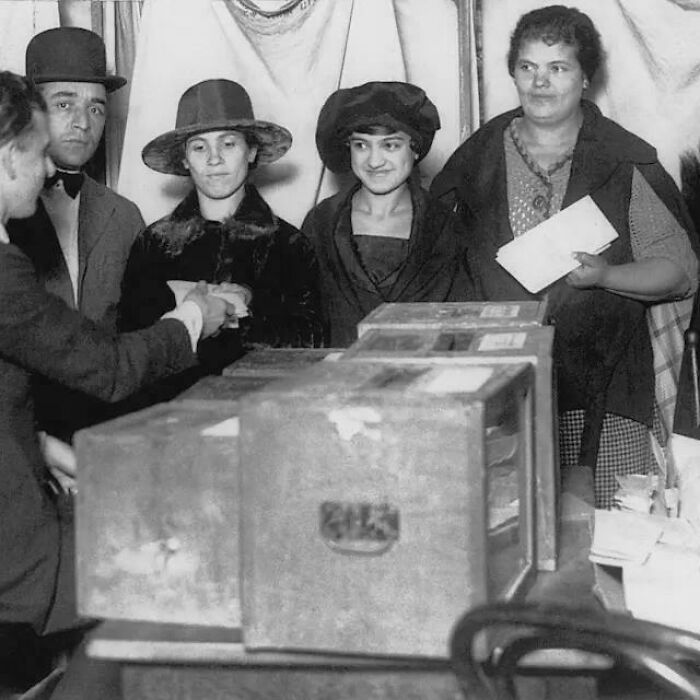 Four women and a man gathered around ballot boxes, a fascinating American history photo.