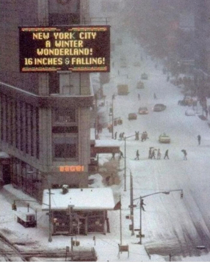 A snow-covered street in New York City with a sign announcing 16 inches of snow, an interesting American history photo.