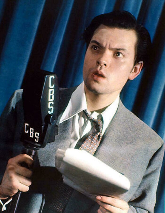 A rare photo from American history shows a man with an expressive face holding a CBS microphone, possibly a radio announcer.