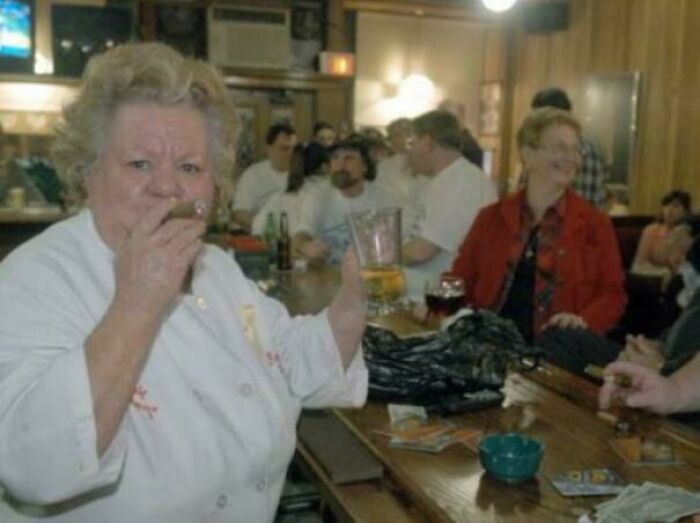 A fascinating photo from American history shows a woman with a cigar in a lively bar setting, surrounded by other patrons.