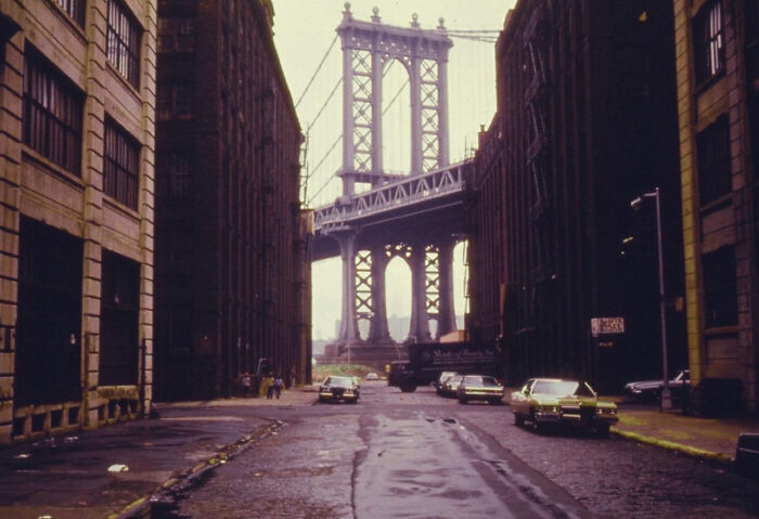A fascinating photo from American history shows a street leading towards the iconic Manhattan Bridge, flanked by old industrial buildings.