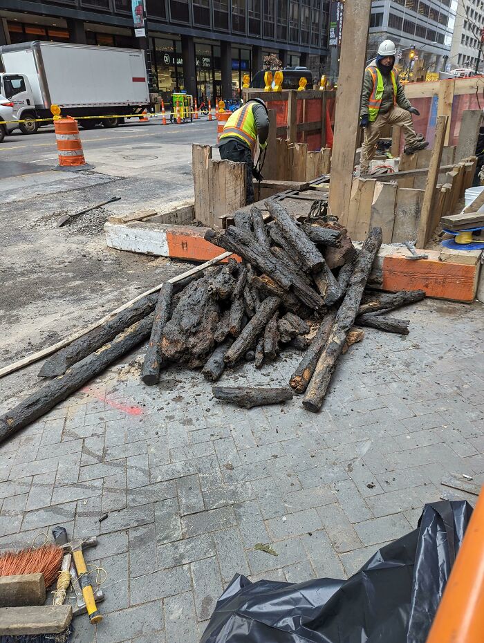 Workers at a construction site revealing fascinating photos from American history, showing old wooden pipes.