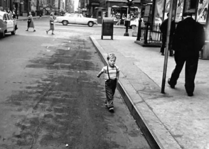 Fascinating black and white photo of a small boy walking beside a street in American history.