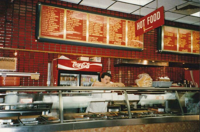 A fascinating photo from American history shows a man behind the counter in a retro diner with a large menu board.