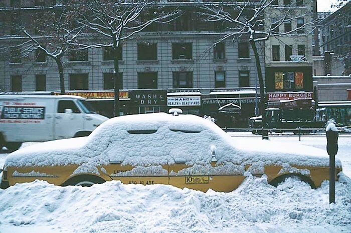 A rare photo from American history shows a yellow taxi buried in heavy snow on a city street.