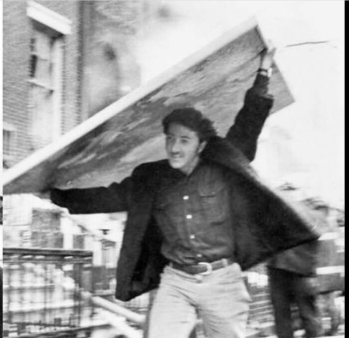 Fascinating American History photo: A man carries a large artwork, running from an unknown event.