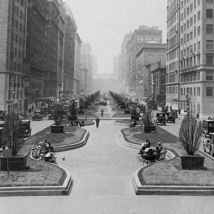 A wide shot of a bustling city street with classic cars and pedestrians, a rare photo from American history.