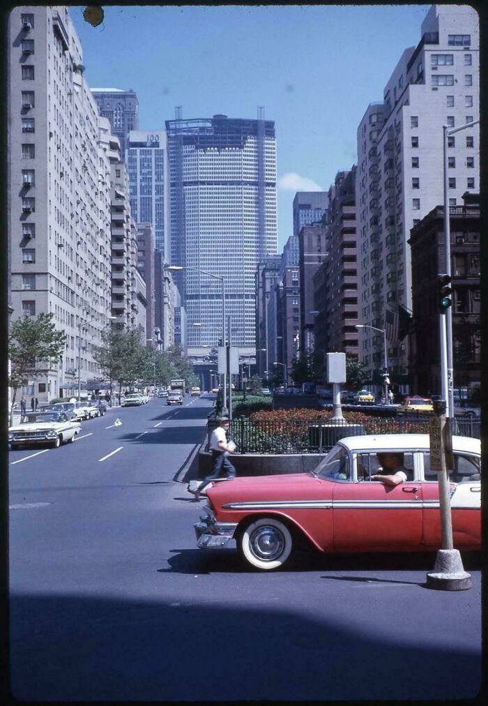 A vibrant street scene with a pink and white vintage car, capturing a fascinating moment in American history.