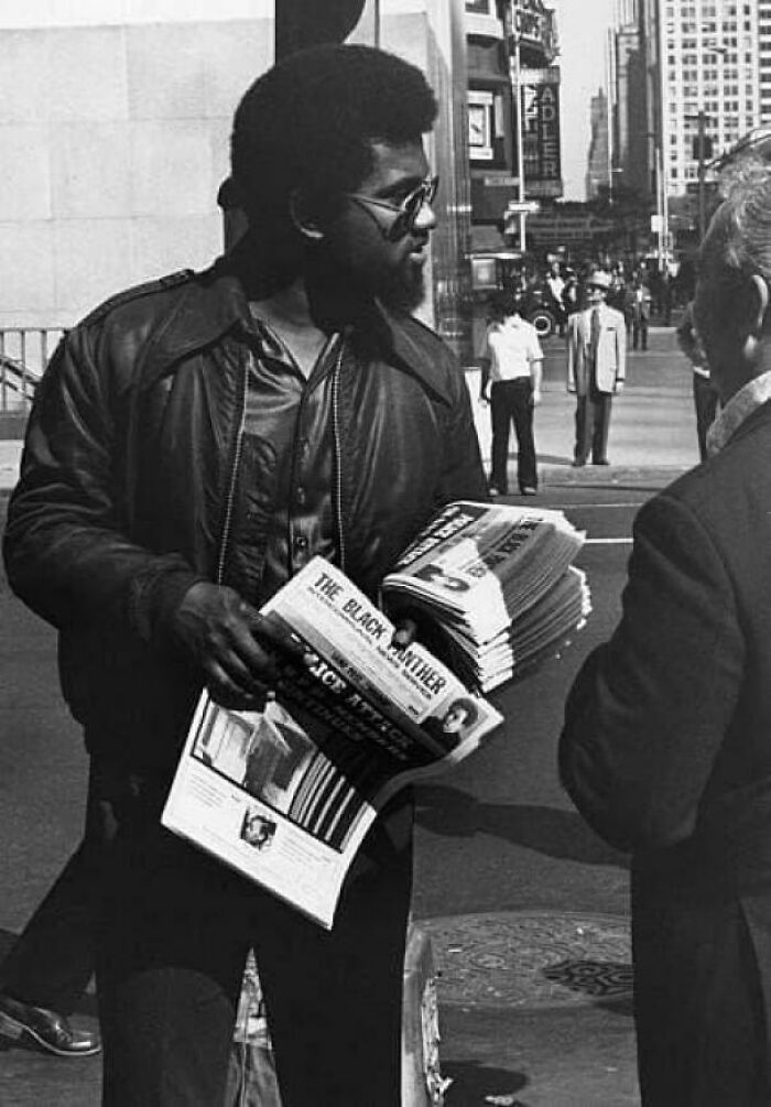 A man selling The Black Panther newspaper in a rare photo from American history, showcasing fascinating historical moments.