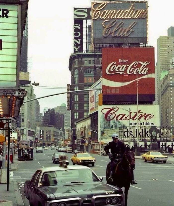 A rare and fascinating photo from American history, showing a busy city street scene with a mounted police officer and classic cars.