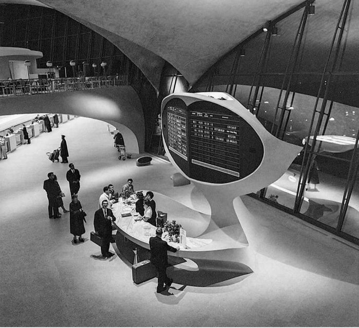 An interior view of a futuristic airport terminal with a large departures board, a fascinating photo from American history.