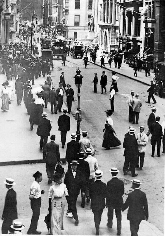 A busy street scene with many pedestrians and horse-drawn carriages, a fascinating photo from American history.