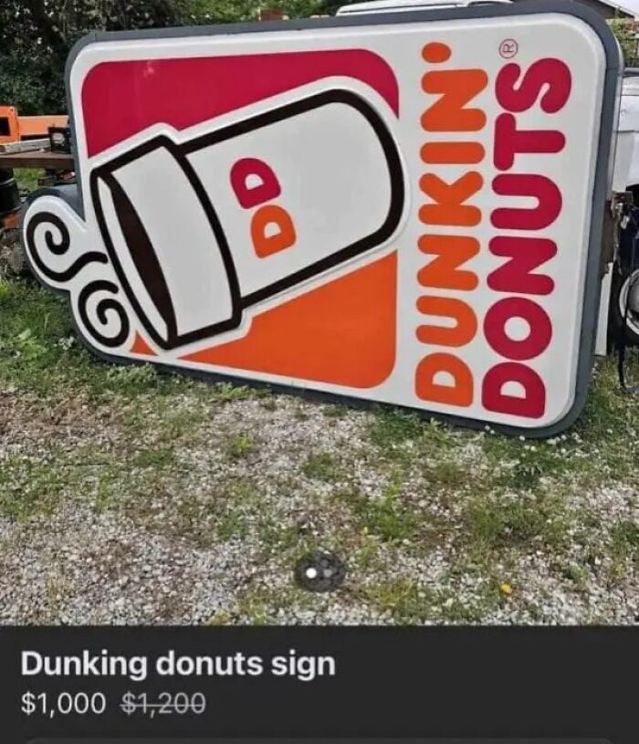 A large, discarded Dunkin Donuts sign lying on the grass, a strange find on an online marketplace.