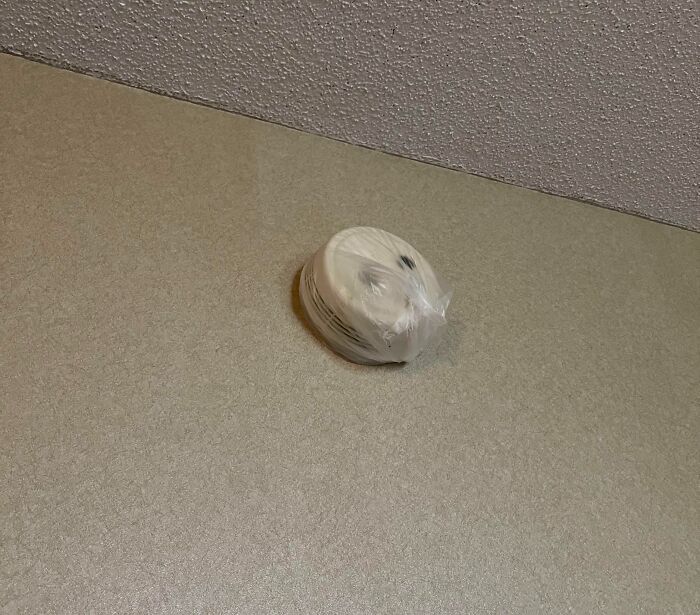 A smoke detector, still in its plastic wrap, sits on a wall, a mildly infuriating obstacle.