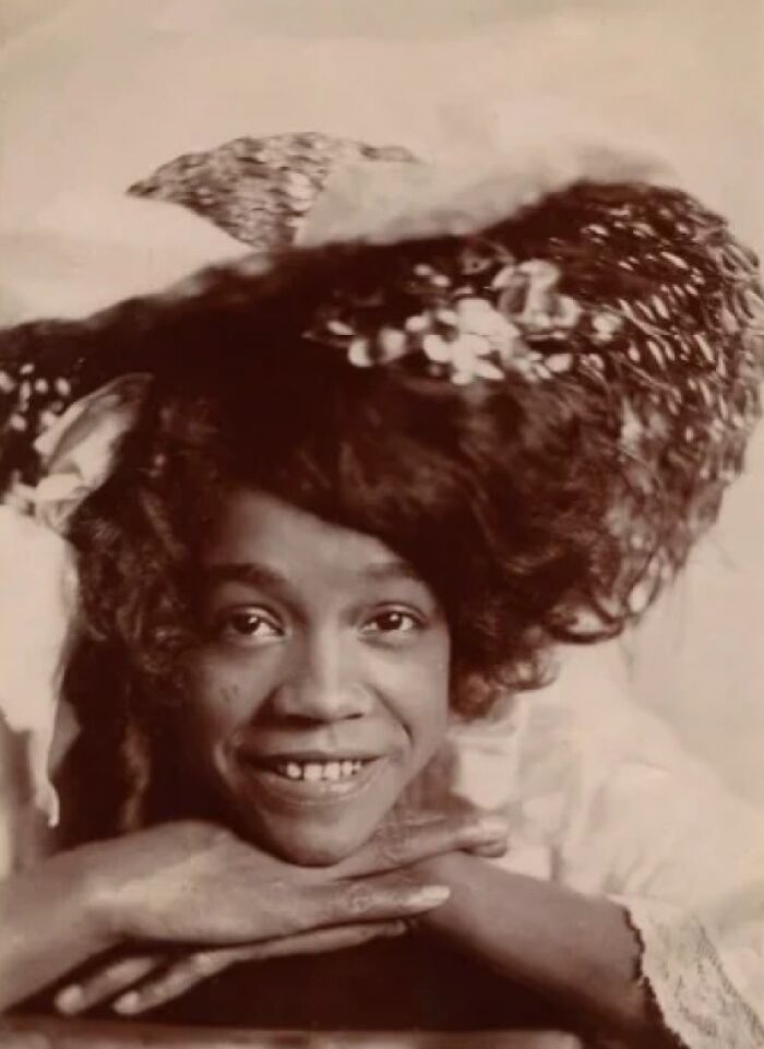 Intriguing Victorian photo of a smiling woman with a large feathered hat, capturing an everyday portrait.