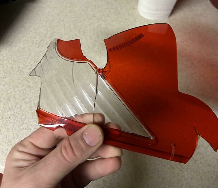 A hand holding a broken piece of red and clear plastic, a thing people lost hope to find.