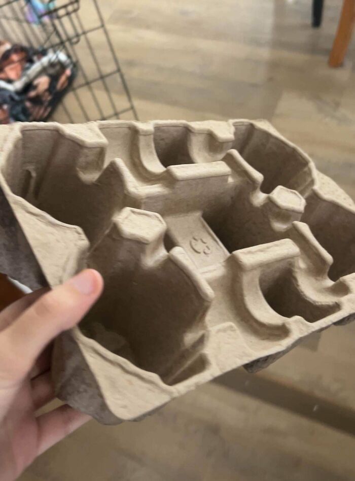 A hand holding a brown cardboard tray, possibly a cup holder, that people lost hope to find.