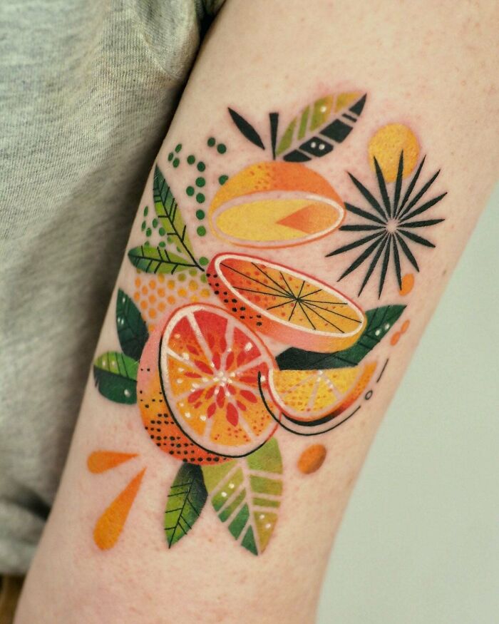 A vibrant, stylized tattoo of citrus fruits and leaves on an arm; internet finds artistic inspiration.