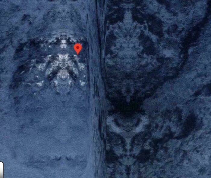 A close-up of a textured, dark surface from Google Maps with a red pin, highlighting an odd find.