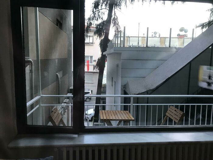 A narrow balcony in an Airbnb listing with a small table and two chairs, showing limited outdoor space.