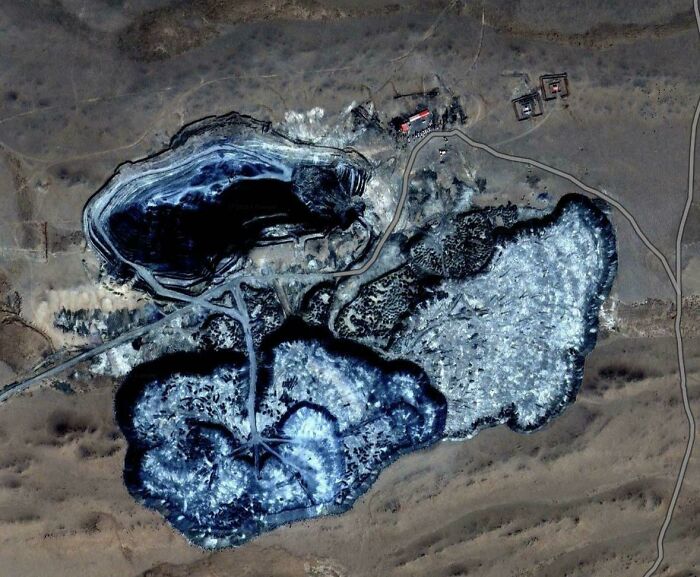 Odd things on Google Maps: An aerial view of unusual, blue-toned industrial ponds or lakes in a barren landscape.