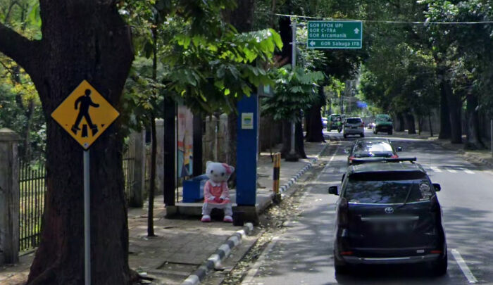 A Hello Kitty character on the sidewalk next to a pedestrian crossing sign, an odd thing found on Google Maps.