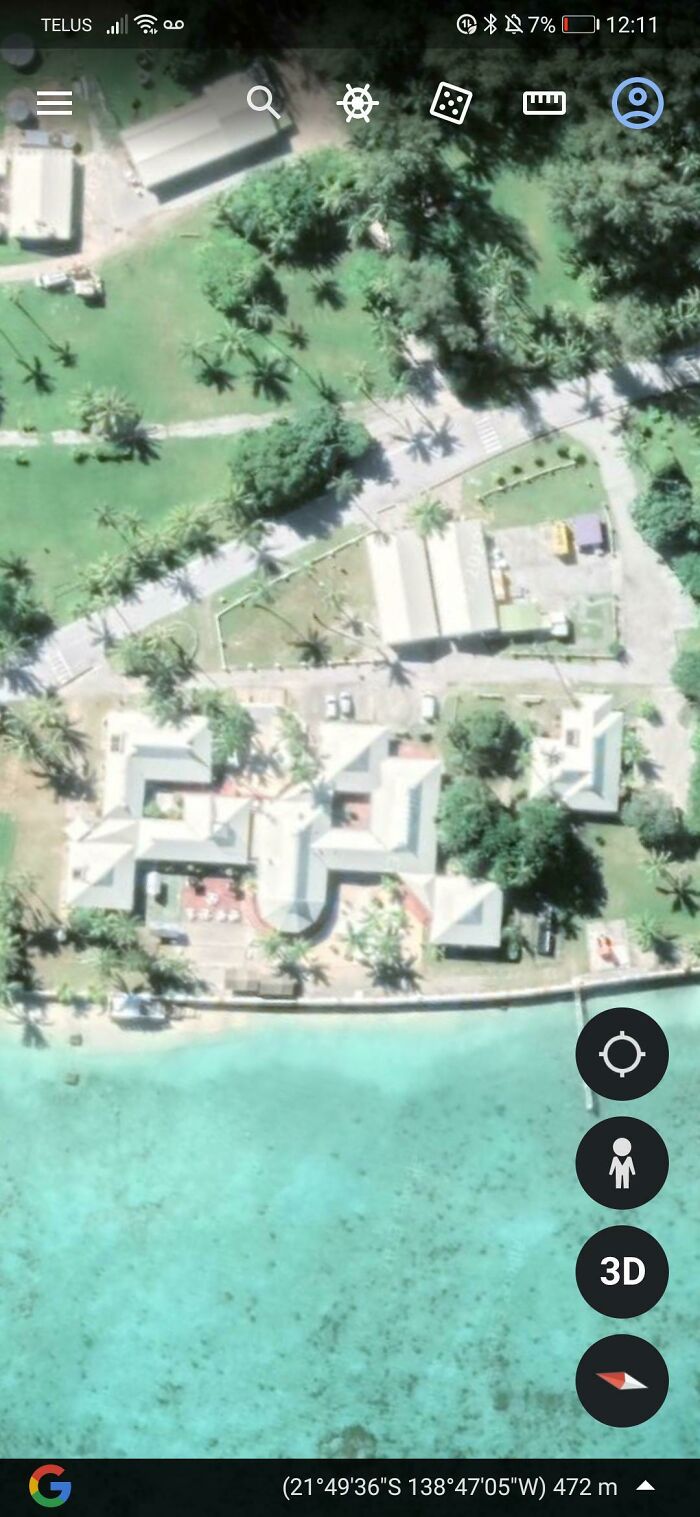 A detailed Google Maps satellite image of a large, intricate building complex by the water, surrounded by palm trees, an odd place.
