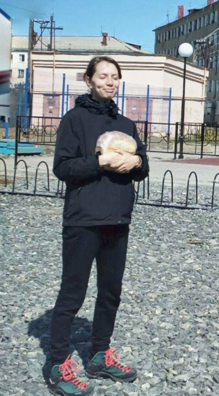 Odd things on Google Maps: a person in black clothing and hiking boots stands outdoors holding a round loaf of bread.