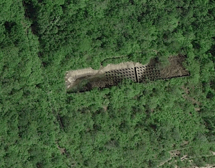 Odd things on Google Maps: an aerial view of a rectangular, man-made structure amidst dense forest.