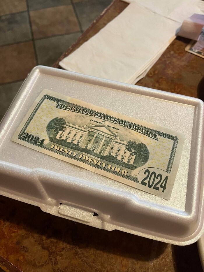 A fake twenty dollar bill with 2024 printed on it, lying on a styrofoam takeout box, representing little hope for humanity.