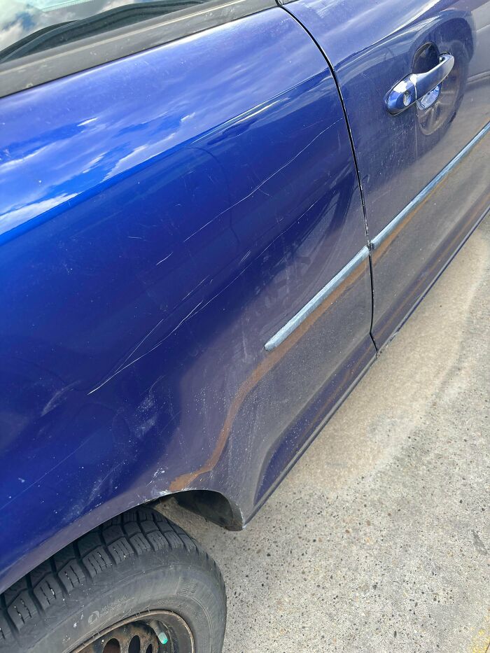 A blue car with scratches on the side, demonstrating little hope for humanity.